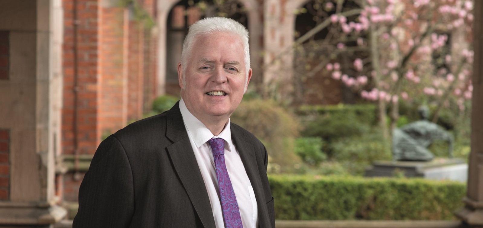 Professor Mark Lawler in jacket and tie in quad at Queen's University Belfast