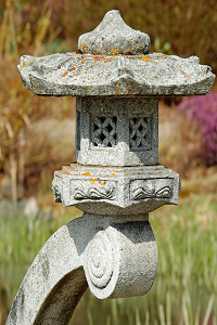 A traditional Japanese lantern made out of stone places outside in an oriental themed garden.