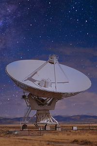 A large radio telescope can be seen against a dark, star-filled night.