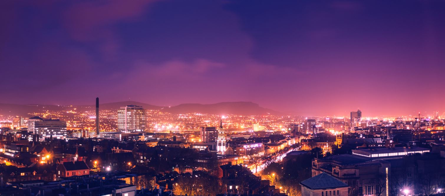 Belfast skyline at night showing street lights, buildings and in the distance Cave Hill in silhouette 
