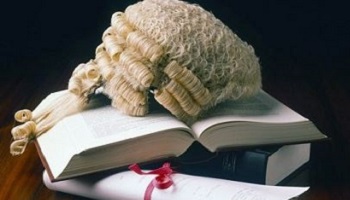 Legal wig, law books and graduation scroll tied with red ribbon