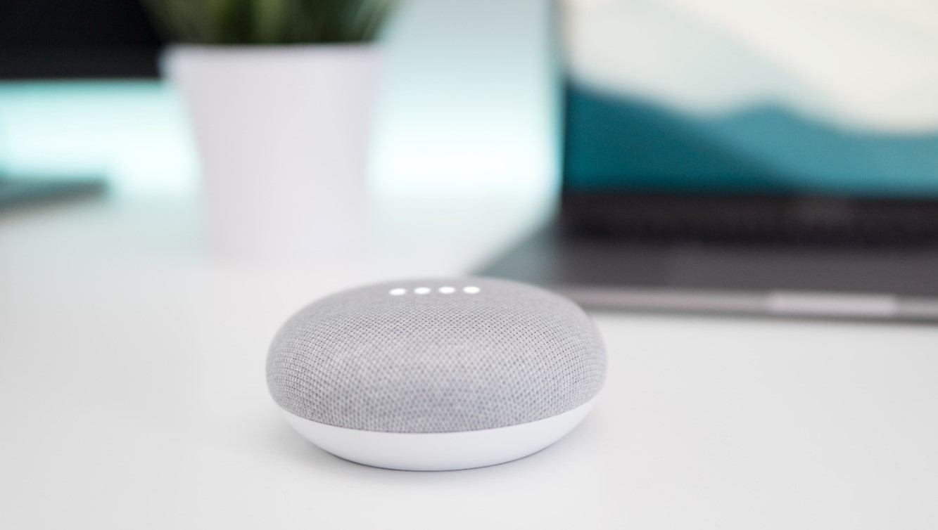 Stylish smart speaker in grey sitting on white table 