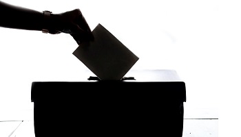 Silhouetted hand placing nomination in ballot box