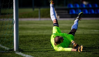 Goalkeeper diving in front of football net 
