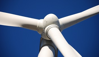 Up close image of three bladed wind turbine against cloudless deep blue sky