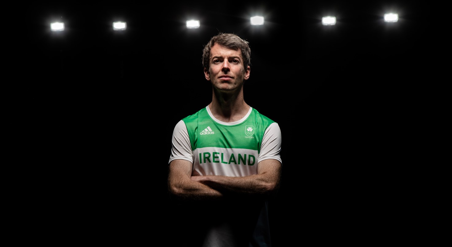 Runner Paul Pollock standing arms folder under spotlights in green jersey of Ireland