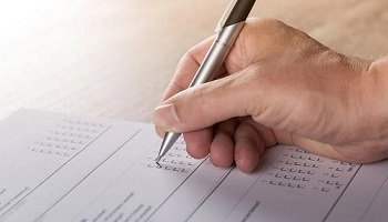 Right handed person holding a pen completing a paper survey