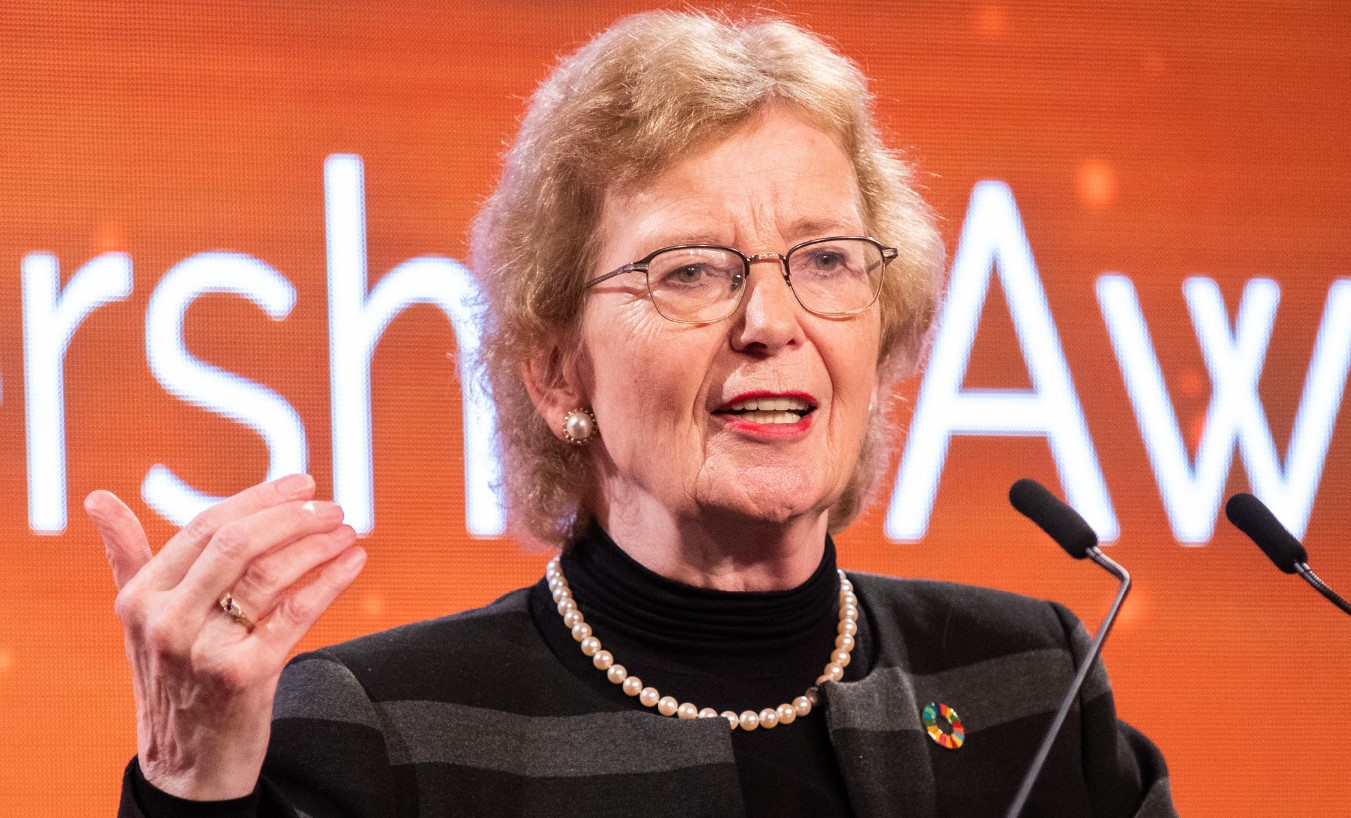 Close up of former Irish President Mary Robinson speaking at podium, against orange coloured background