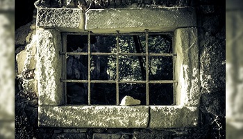 Exterior view through dilapidated prison window 