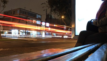 Women sitting on bus stop bench as traffic passes