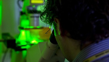 Researcher in lab using microscope in green light