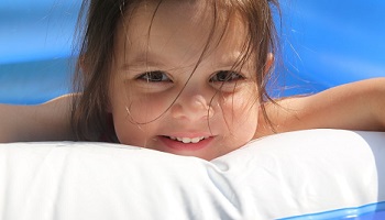 Smiling young girl showing her teeeth lying on lilo in swimming pool