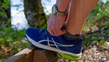 Male runner tying lace, with foot up on bench