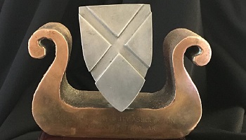 Brass trophy using outline of AIB logo (in shape of a boat) and crest / shield of Queen's University