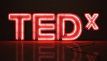 TEDx logo in red and white neon - large T-E-D in capital letters and small X (also in capitals) 