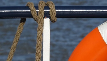 Rope on ferry railing beside lifebelt 
