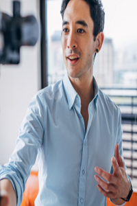 Man in blue open neck shirt delivering a talk to video camera