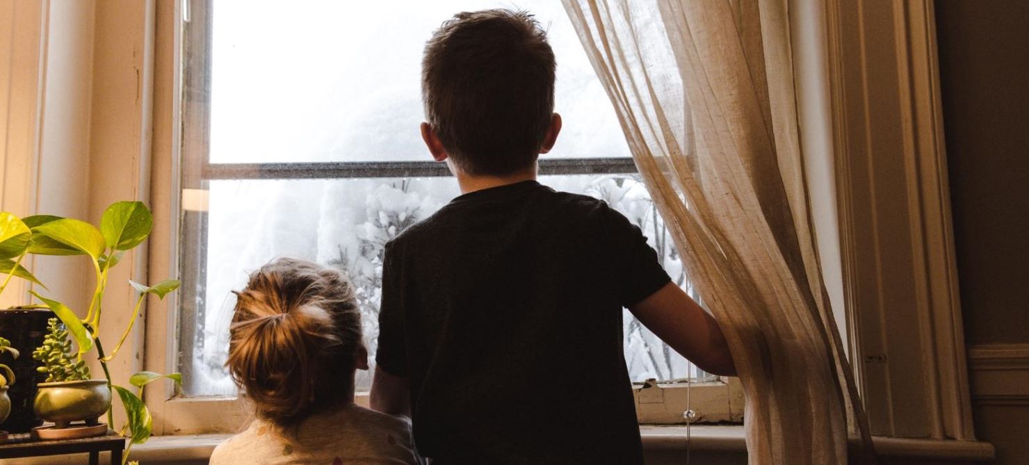 Two children, backs turned, looking out window