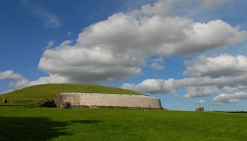 Newgrange burial site grassy mound against blue sky 